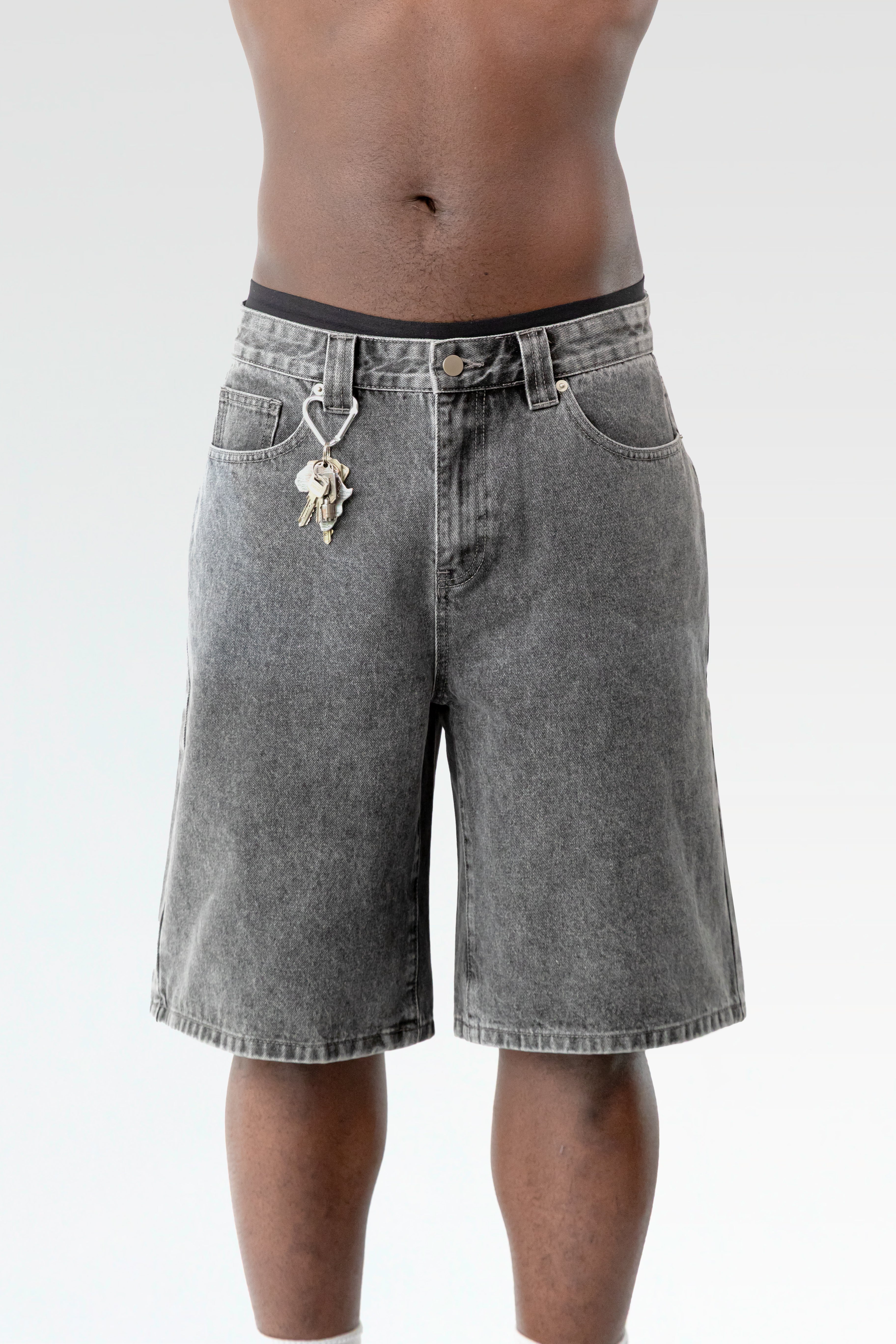 Nahaufnahme der hellgrau verwaschenen Bermuda-Shorts im getragenen Zustand, mit Fokus auf den Karabinerhaken samt Schlüsselbund an der Gürtelschlaufe.