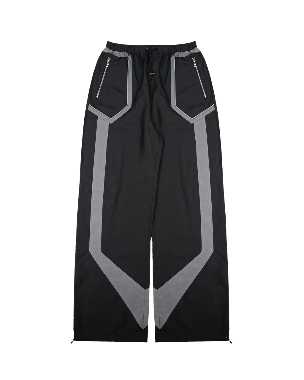 Schwarze, weit geschnittene Hose mit grauen geometrischen Einsätzen entlang der Beine. Der elastische Bund ist mit Tunnelzug ausgestattet. Zwei schräge Fronttaschen mit silbernen Reißverschlüssen und markanter Paspelierung runden das sportlich-technische Design ab.