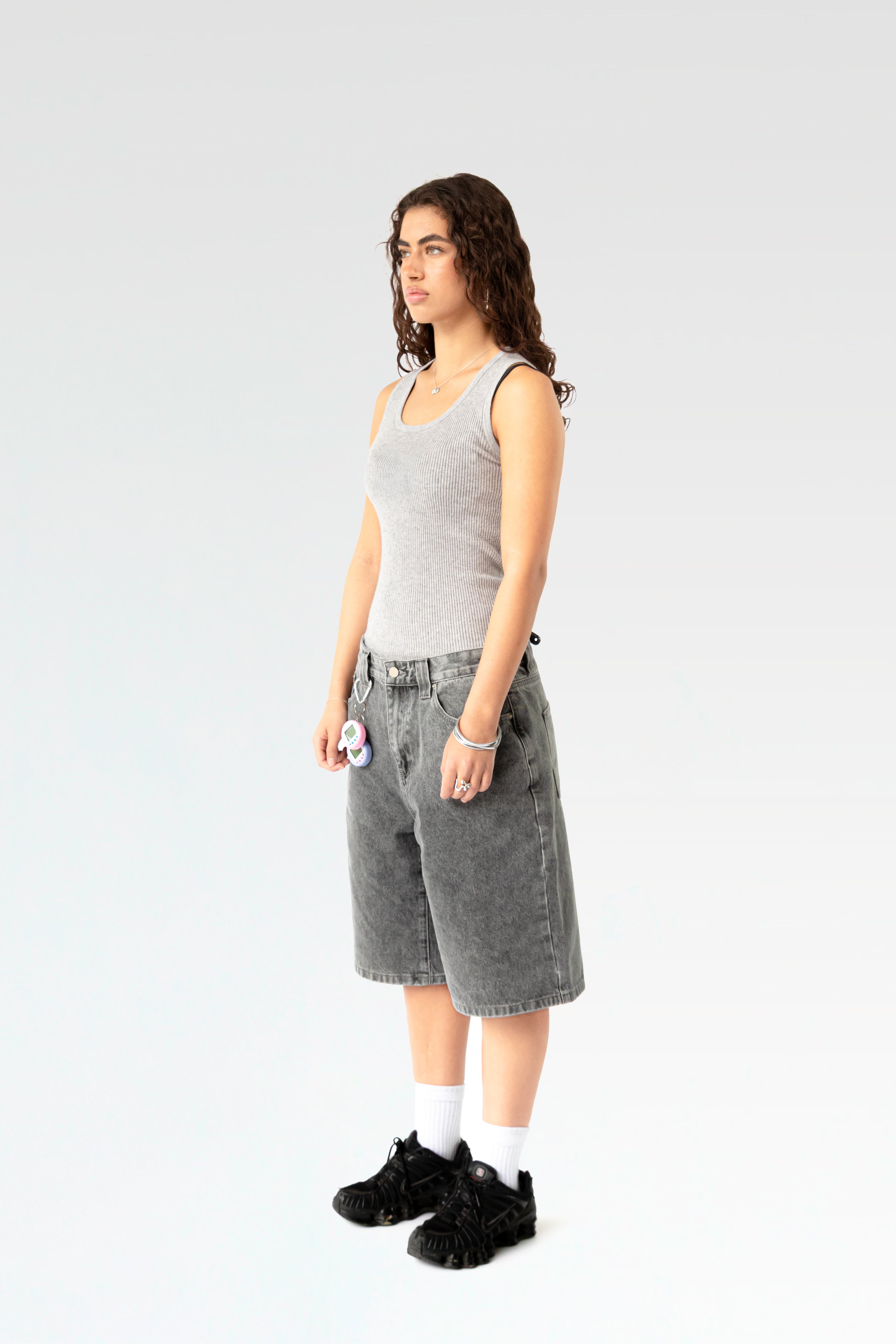 Schräg seitliche Ansicht der hellgrau verwaschenen Bermuda-Shorts an einer stehenden Person. Die weite Beinform und die klassische 5-Pocket-Optik sind gut sichtbar.