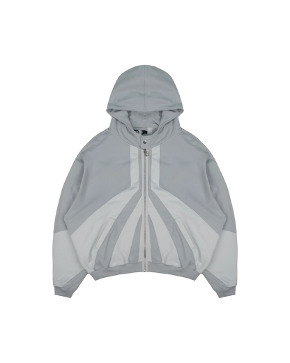  Hell grau Zip-Hoodie mit Kapuze, großflächigen dunkelgrauen Kontrasteinsätzen auf Brust und Ärmeln sowie auffälliger geometrischer Teilung auf der Vorderseite.