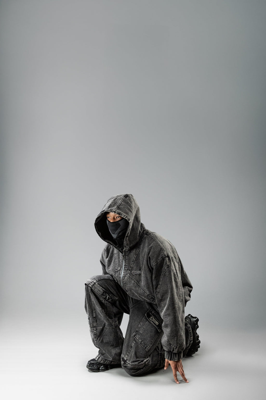 Die Cargohose wird vom Model in Kombination mit einem passenden Hoodie getragen. Die Hose fällt weit über die Schuhe, seitliche Taschen mit Patten und Nähdetails sind klar sichtbar. Die Kniepartie ist markant abgesetzt.