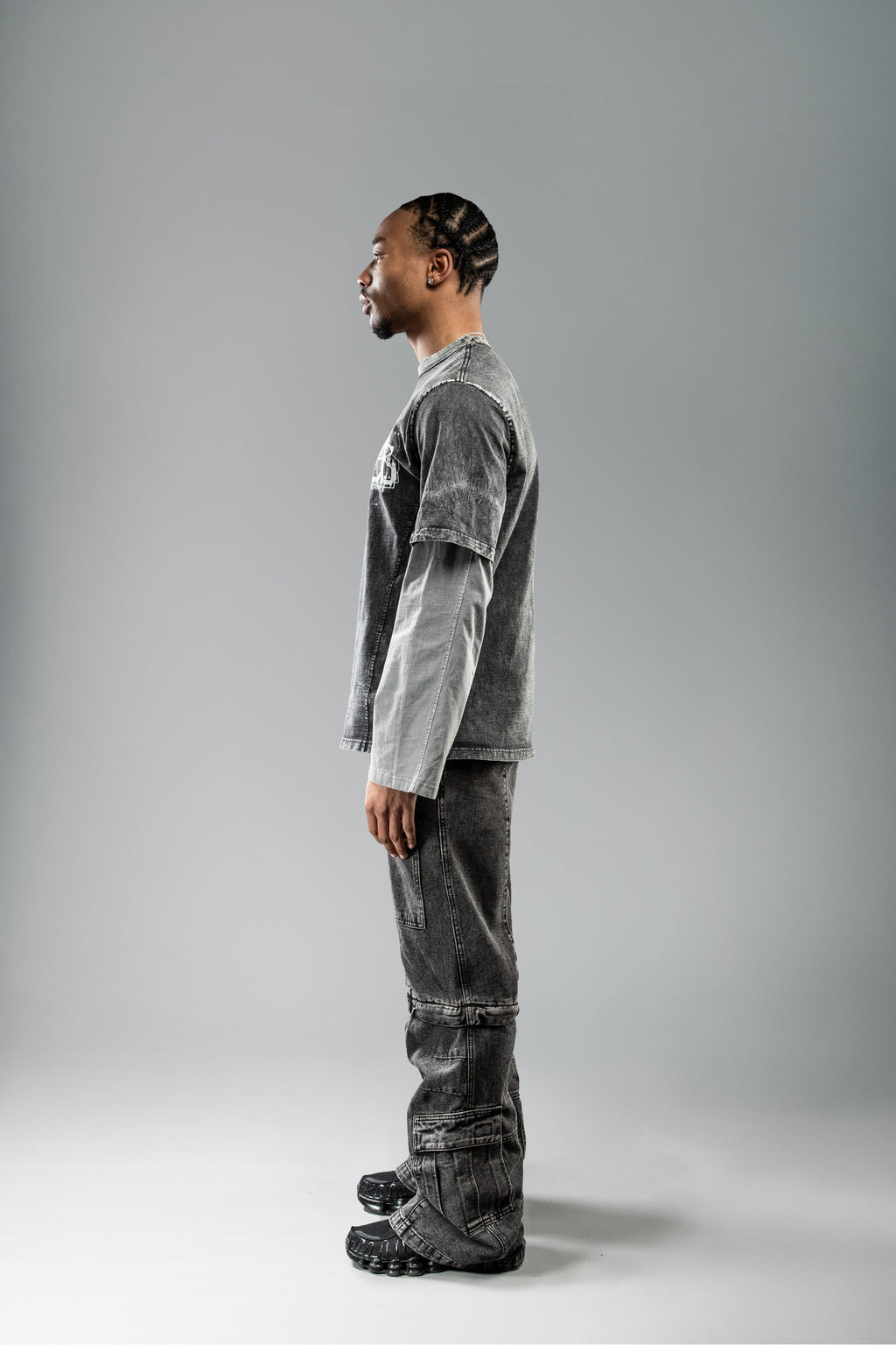 Seitliche Studioansicht des schwarzen Layering-Shirts. Der zweifarbige Aufbau des Shirts sowie die Nahtdetails und die verwaschene Struktur des Stoffes sind deutlich erkennbar.
