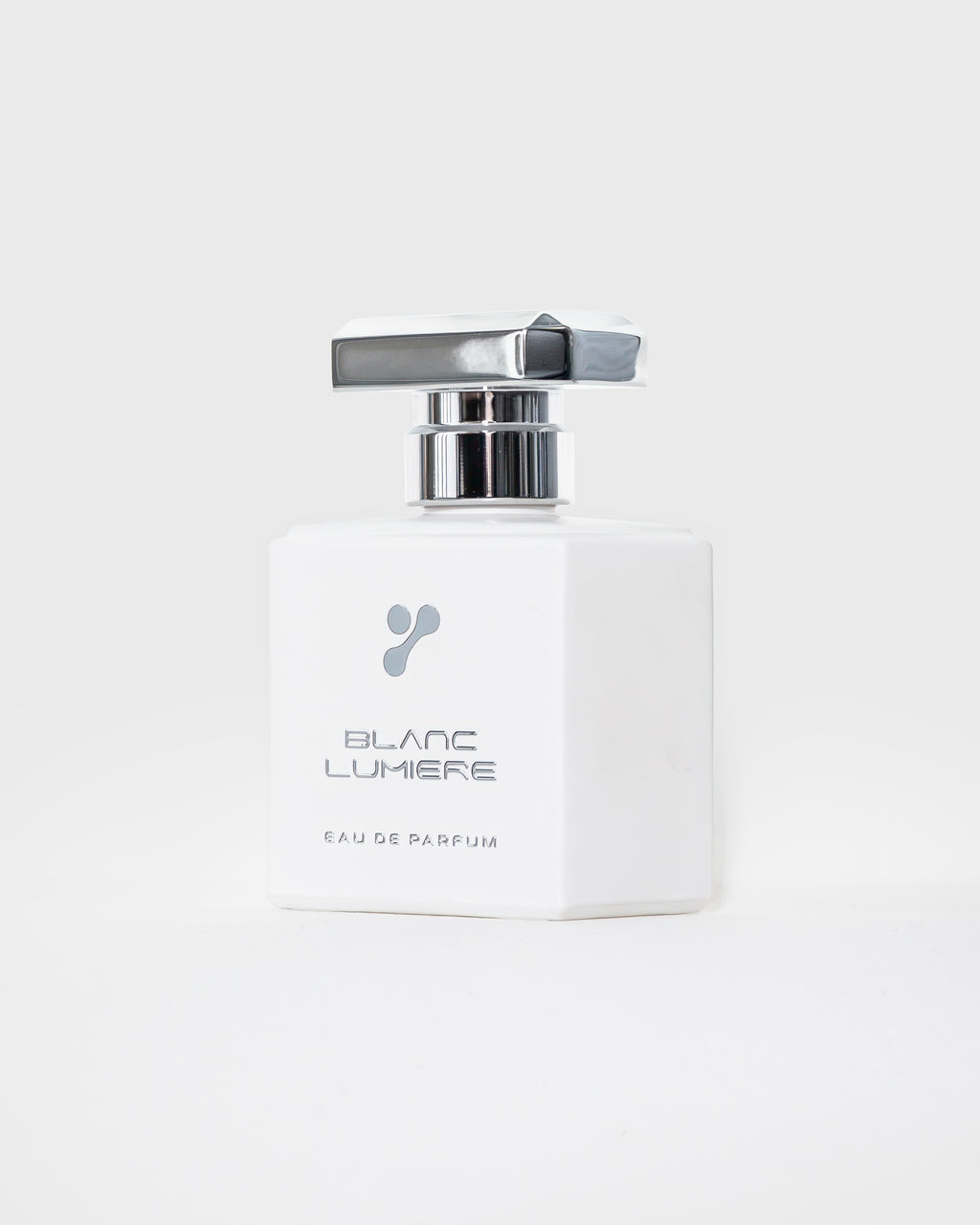 Weißer Parfumflakon schräg von vorn mit Logo und Schriftzug „BLANC LUMIERE – Eau de Parfum“, silberner Deckel.