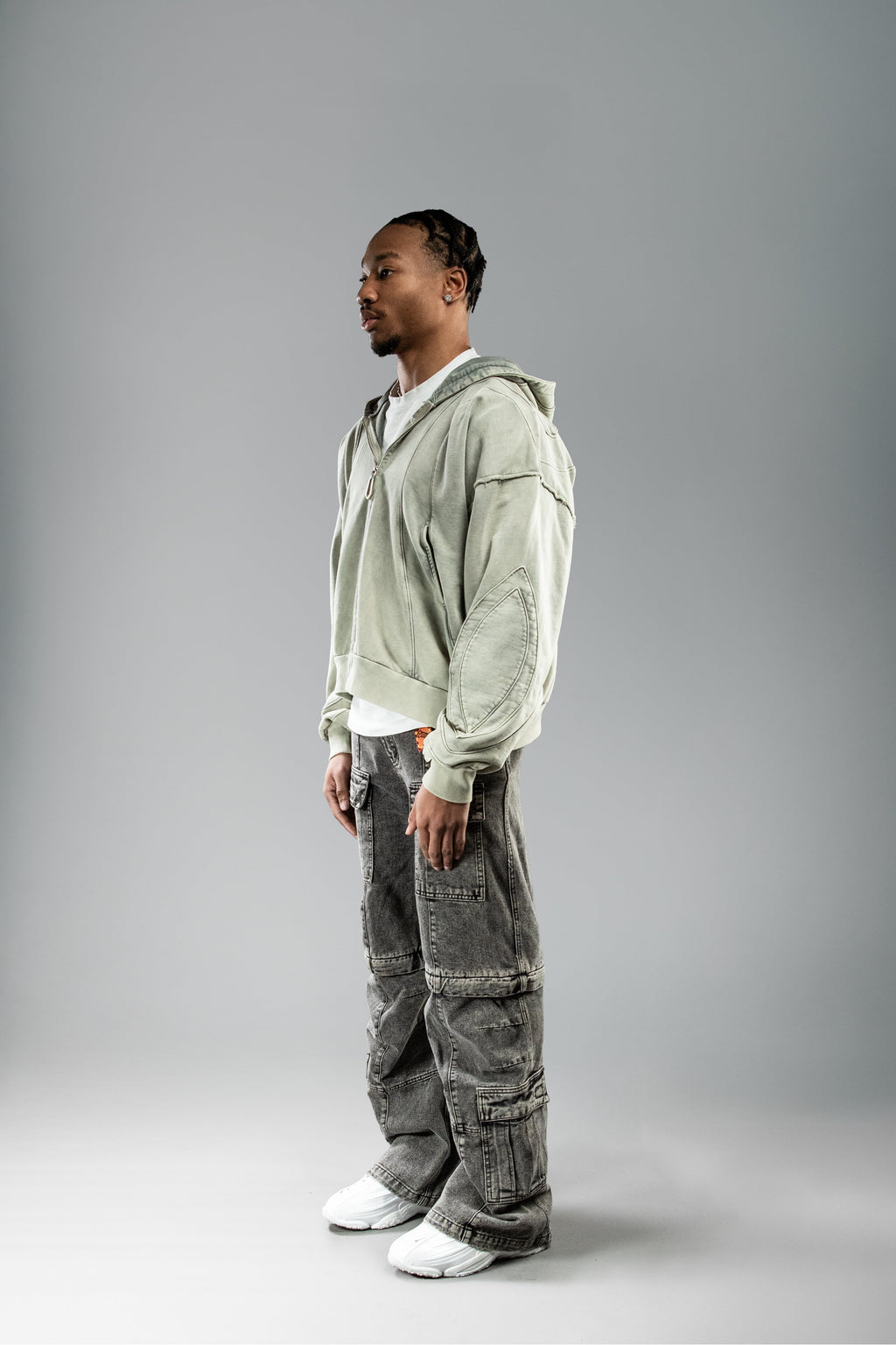 Seitenansicht getragen: Hoodie locker geschnitten, dreidimensional wirkende Nähte auf Ärmel sichtbar.