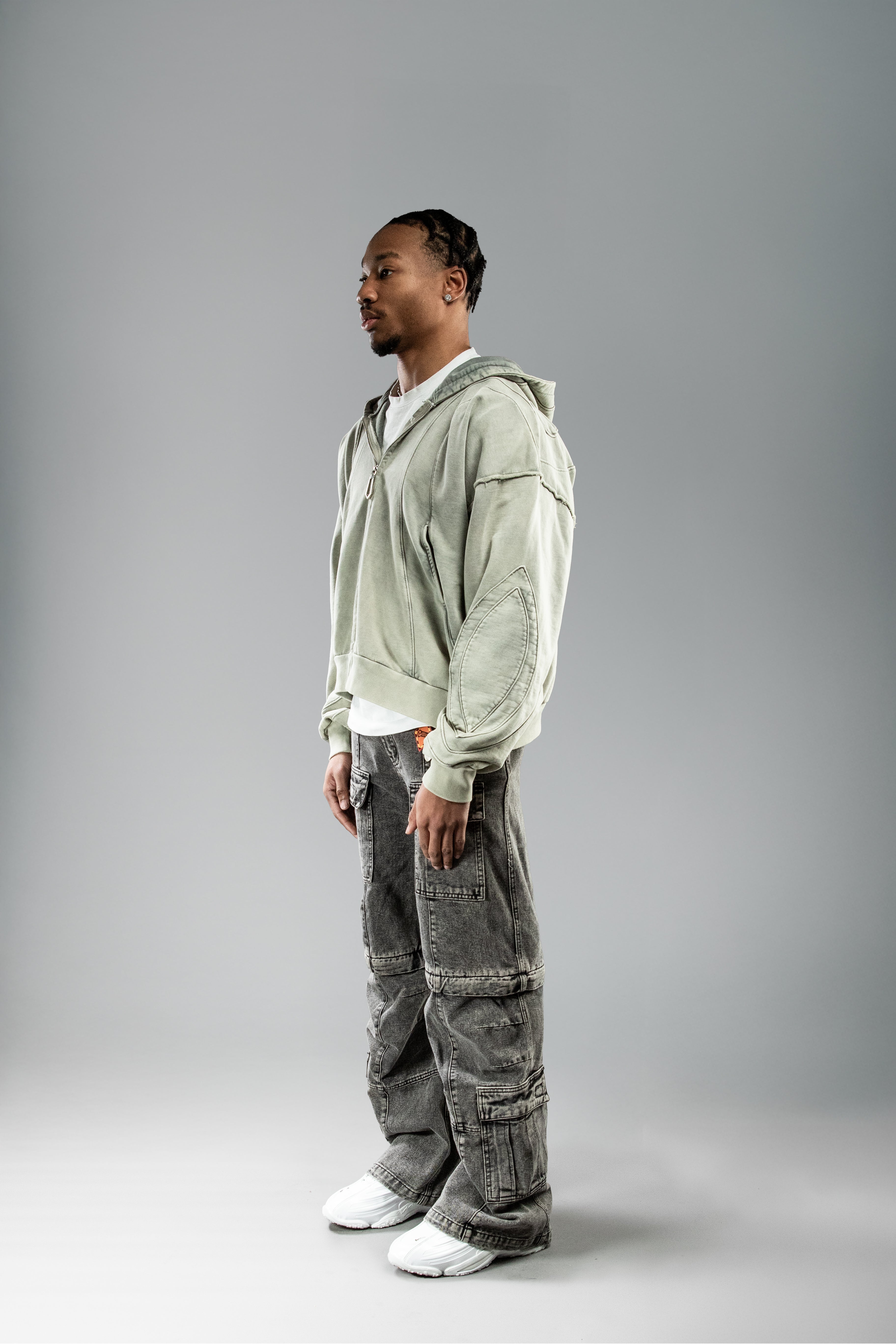 Seitenansicht getragen: Hoodie locker geschnitten, dreidimensional wirkende Nähte auf Ärmel sichtbar.